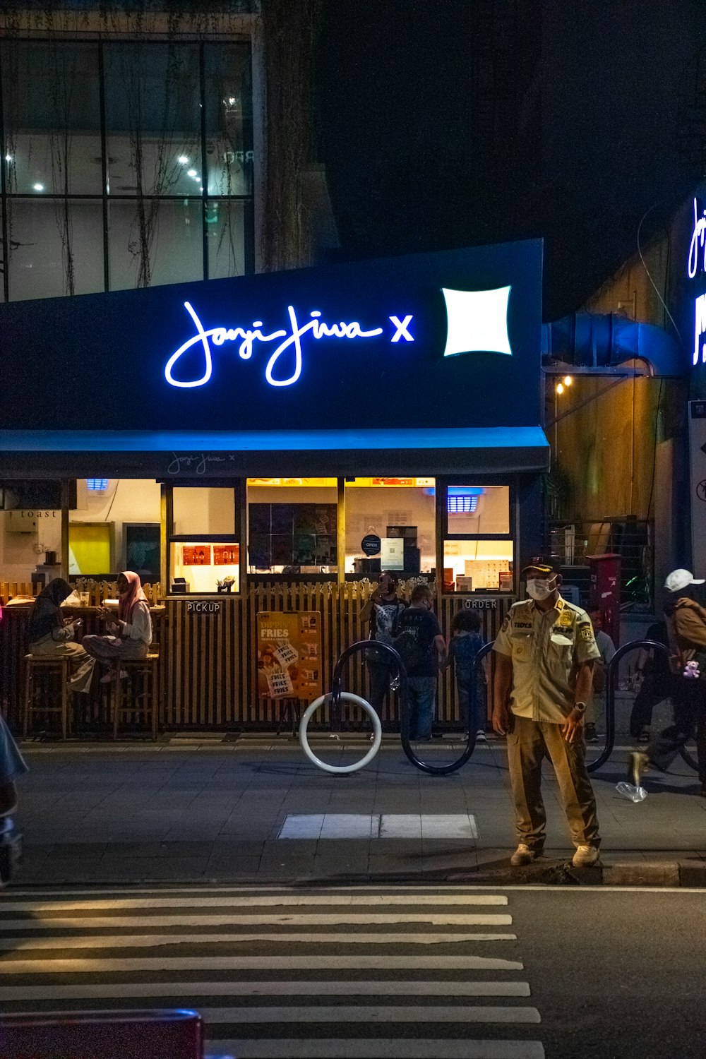 Un gruppo di persone in piedi fuori da un ristorante di notte