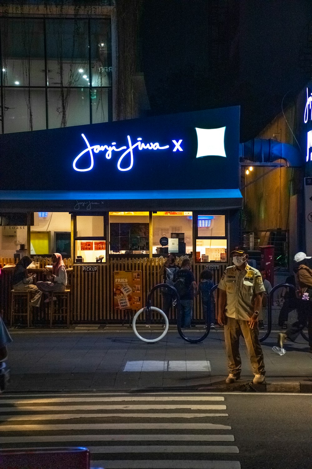 a group of people standing outside of a restaurant at night