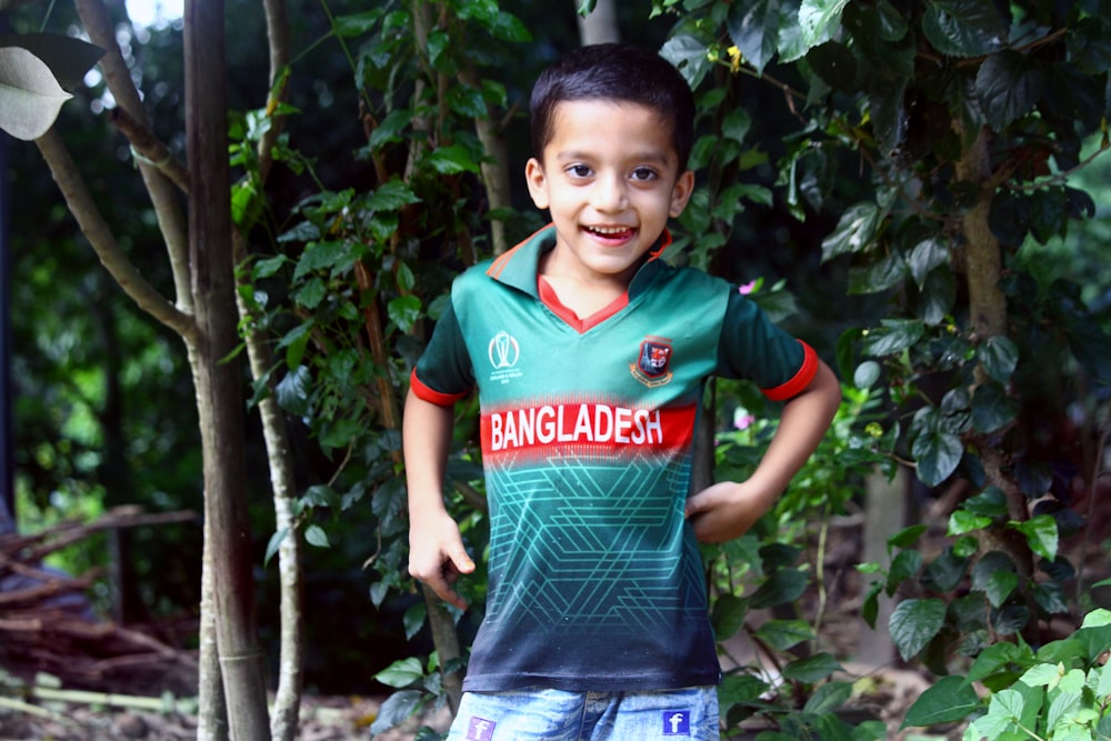 a young boy standing in front of a tree