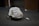 A person wearing a white jacket covered in various handwritten messages is kneeling on the carpeted floor with their head bowed down. Beside them on the floor is an empty aluminum can. The background includes wooden paneling and an elevator door.
