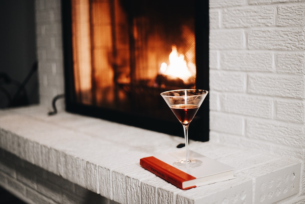 a glass of wine sitting on top of a table next to a fireplace