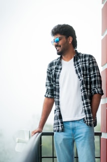 A casual outfit featuring a crisp white shirt and tailored trousers on a sunlit balcony.