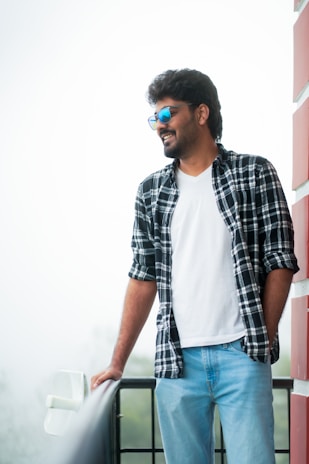 A casual outfit featuring a crisp white shirt and tailored trousers on a sunlit balcony.