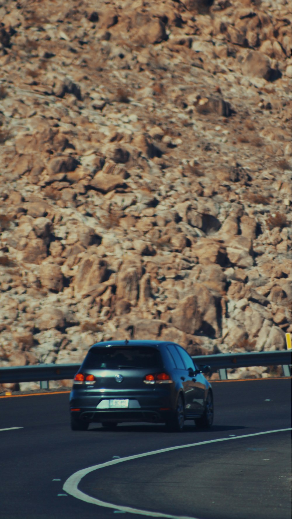 a car driving on a road with a mountain in the background