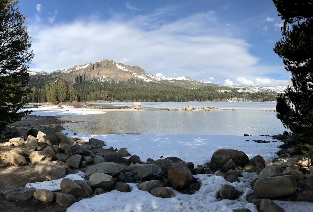 un lago rodeado de rocas y árboles cubiertos de nieve