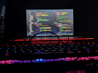 Hands typing on a laptop keyboard with code and AI data visualizations glowing on the screen.