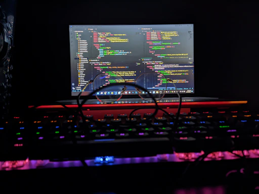 A sleek laptop displaying quantum computing code with a glowing qubit graphic in the background.