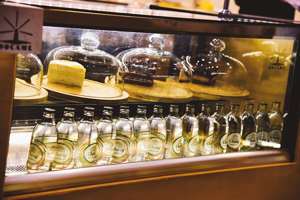 a display case filled with lots of cakes and drinks