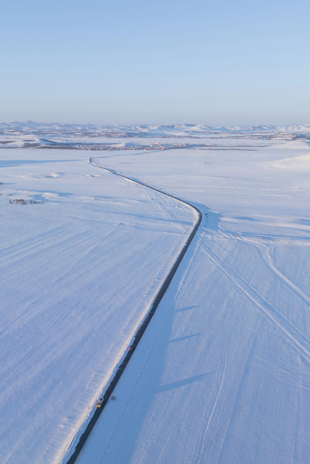 a snow covered field with a road running through it