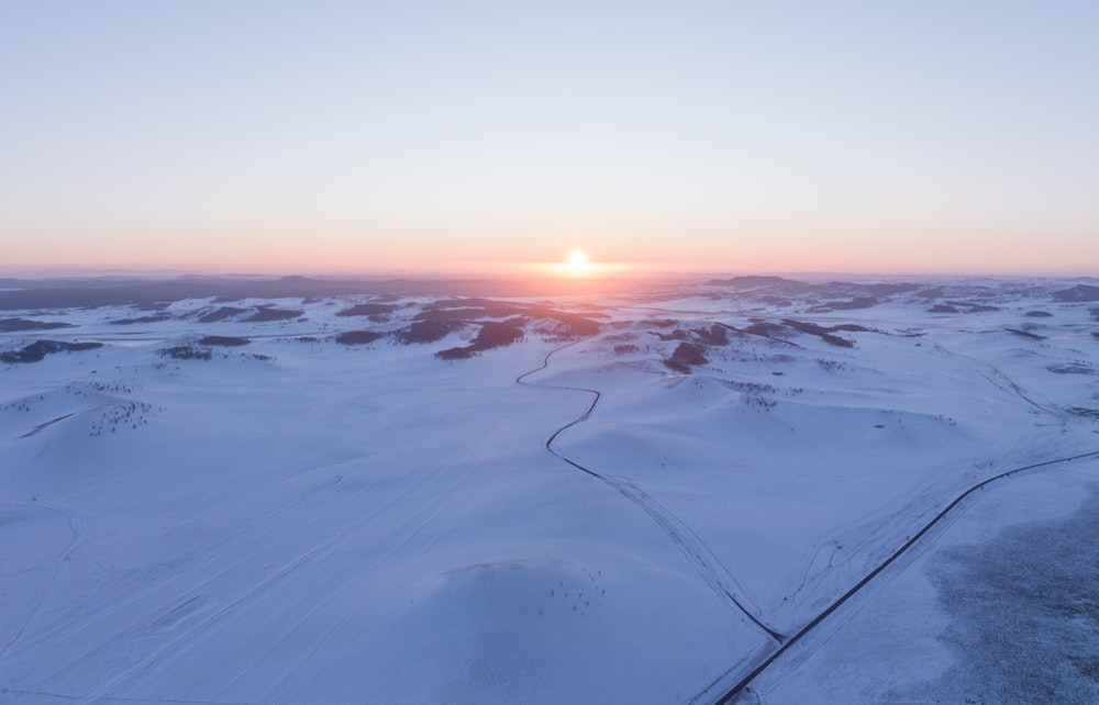 the sun is setting over a snowy landscape