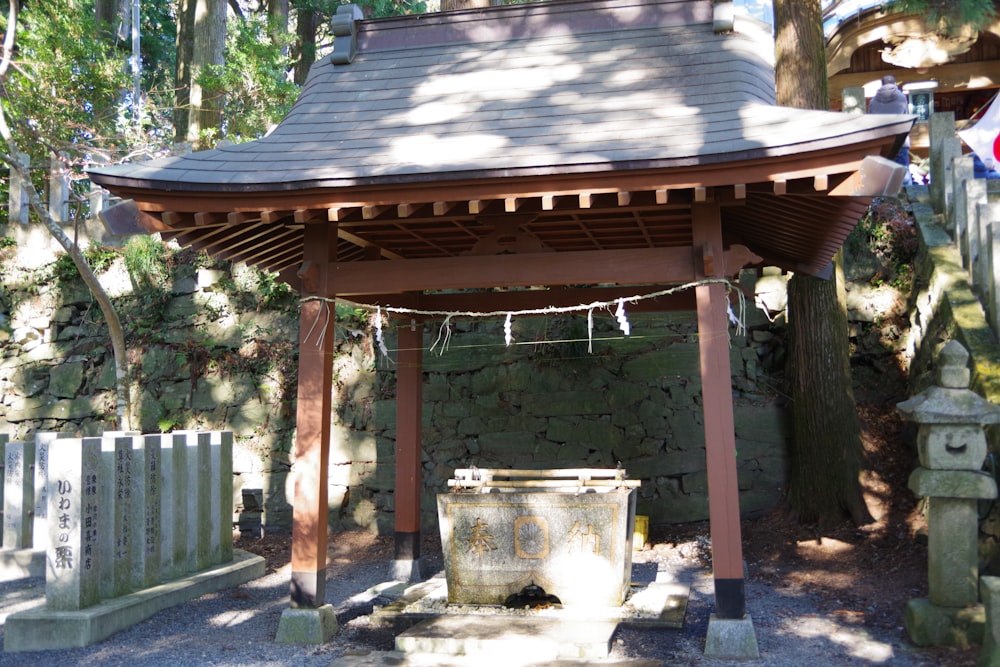 a wooden gazebo with a trash can underneath it