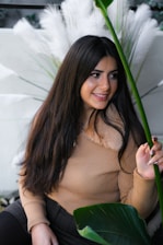 A serene woman in her 40s smiling gently while surrounded by soft natural light and greenery.