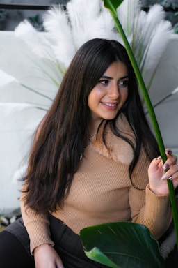 A warm, inviting photo of Ofelia smiling gently in a cozy room filled with plants.