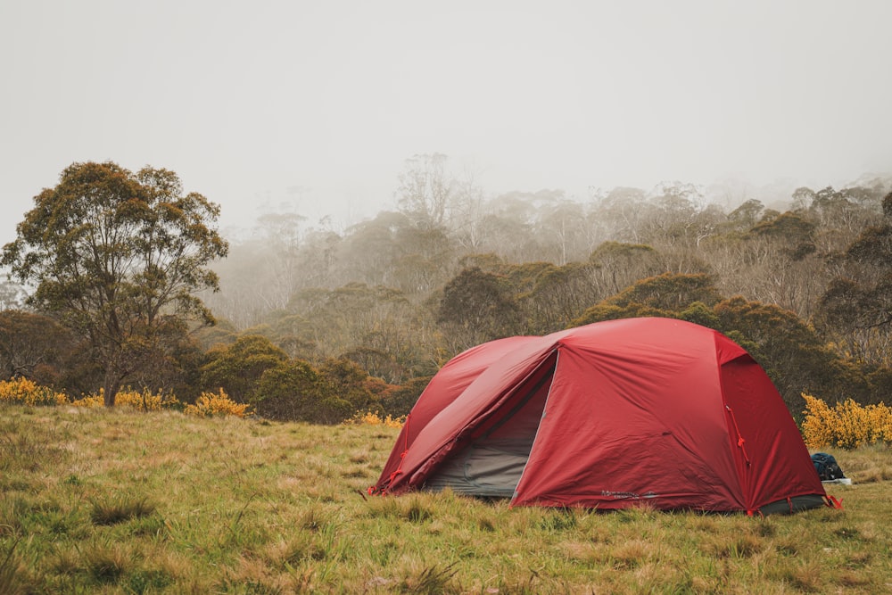 a red tent in a field with trees in the background