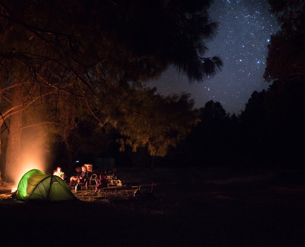 a tent is lit up in the dark by a campfire