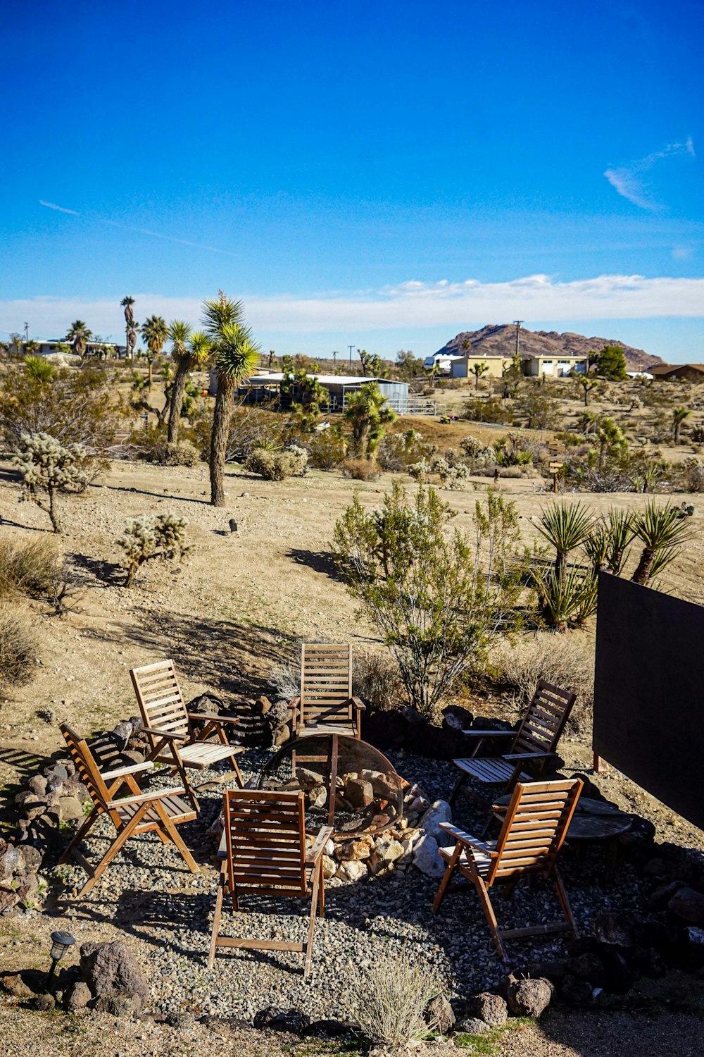 a group of wooden chairs sitting on top of a dry grass field