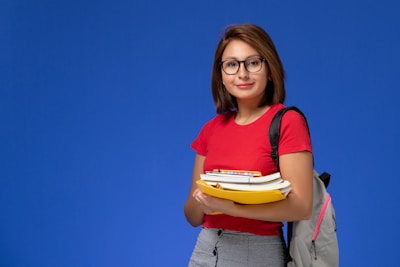 a girl with glasses holding a bunch of books