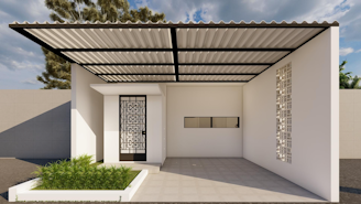 A modern carport with a geometric patterned gate and a flat roof, adjacent to a small garden area containing lush green plants. The structure includes a decorative wall with intricate cut-outs and a horizontal slit window, set against a beige and white tiled ground with a few visible trees in the background.