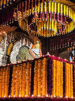 Golden floral decorations framing the mandir entrance in a striking contrast against black walls.