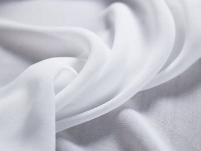 Soft, flowing white fabric creates delicate folds and curves, evoking a sense of smoothness and elegance.
