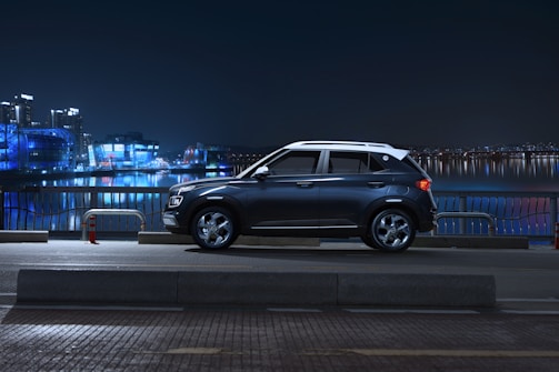 A sleek deep blue premium SUV parked against a modern Dubai skyline at dusk.