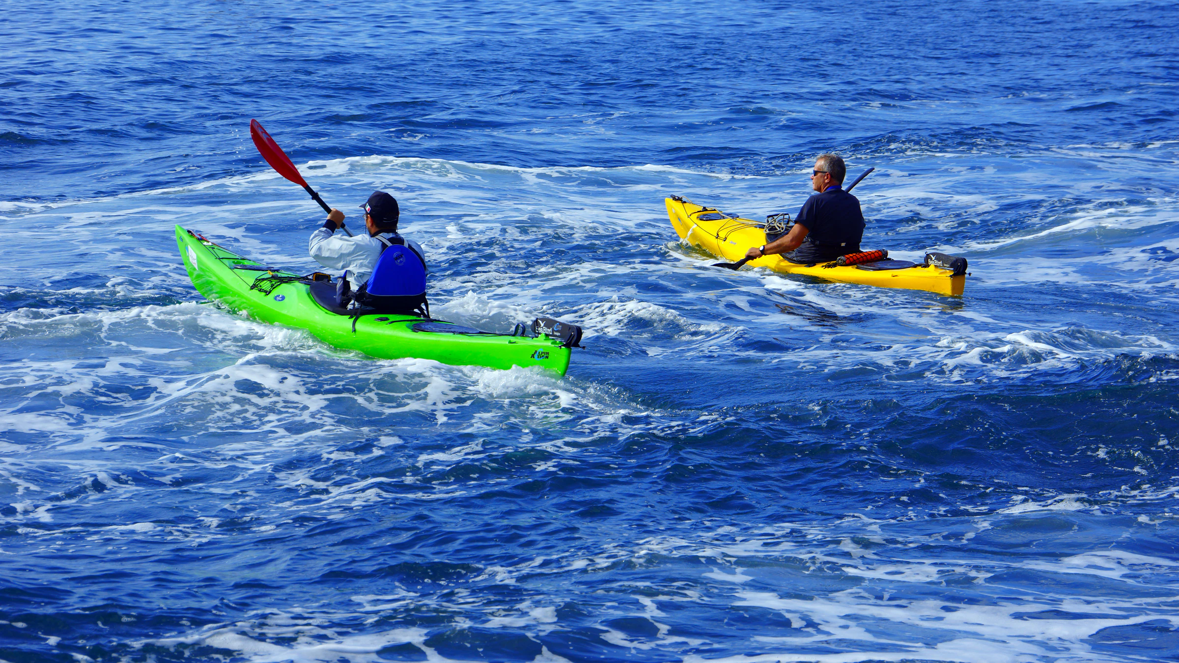 Two paddlers kayaking together across open ocean water