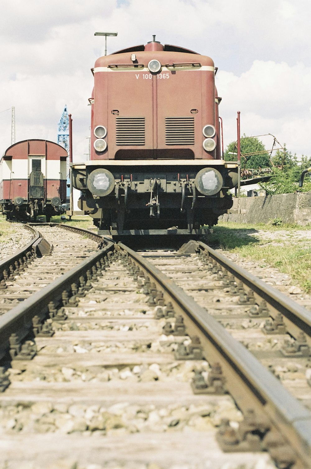 a red train traveling down train tracks next to a field