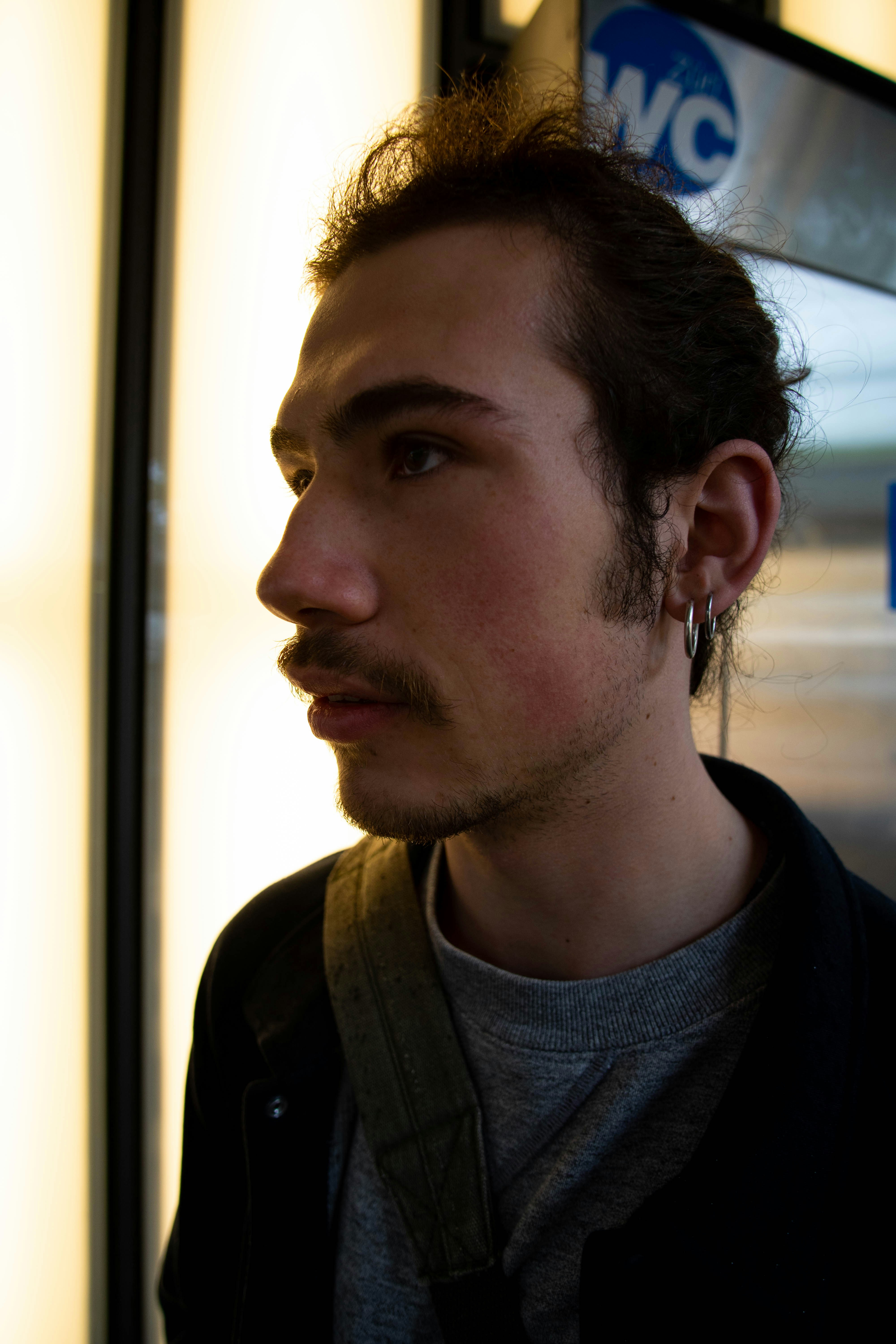a man with a goatee and earring standing in front of a window