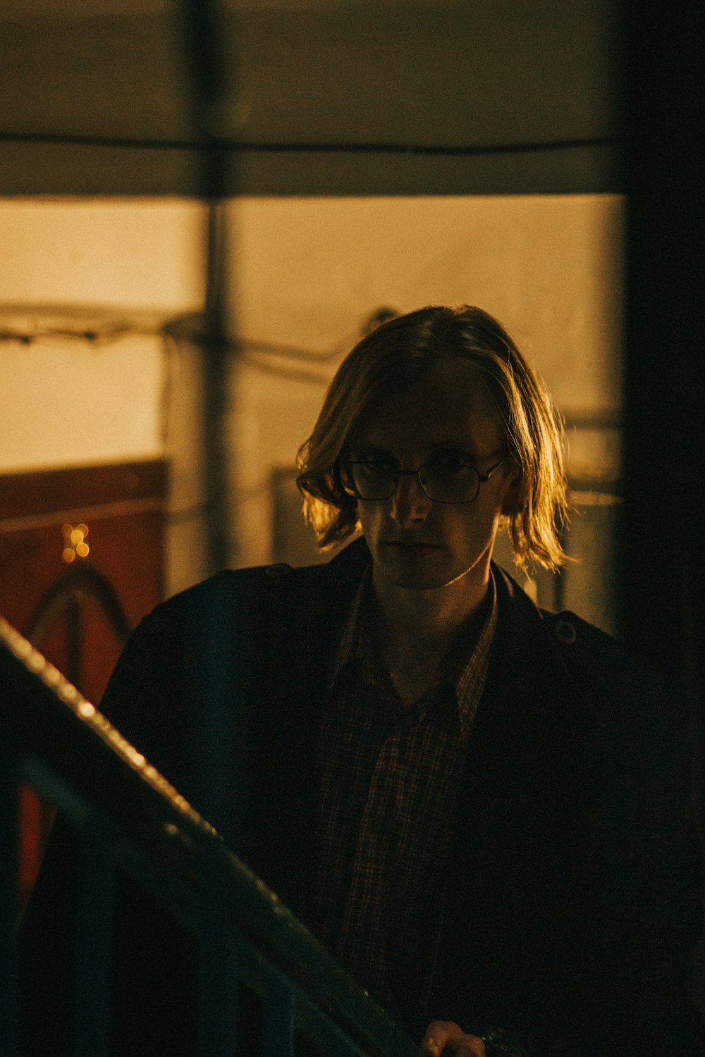 a man with glasses standing next to a stair case