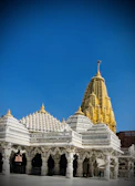 The golden spires of Kashi Vishwanath Temple glowing under a clear blue sky.