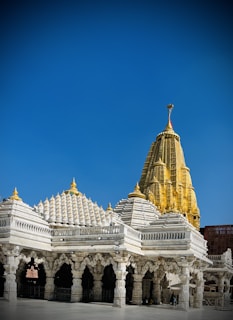 The golden spires of Badrinath temple glowing warmly under a clear blue sky.