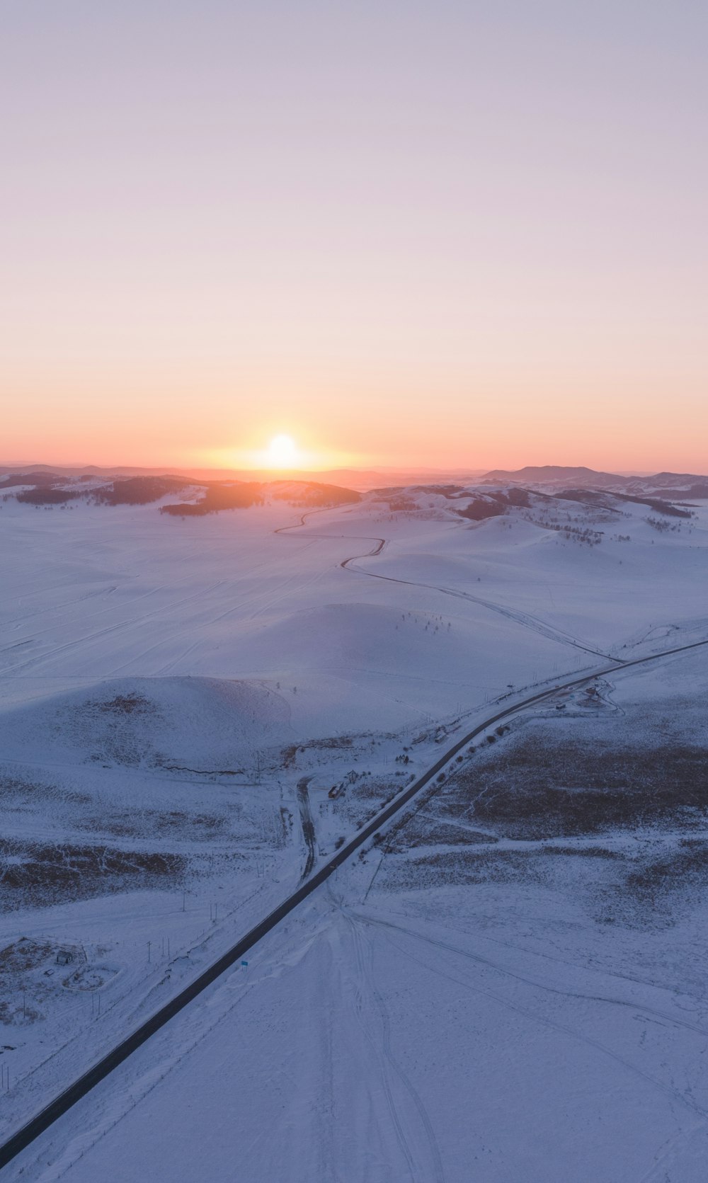 the sun is setting over a snowy landscape