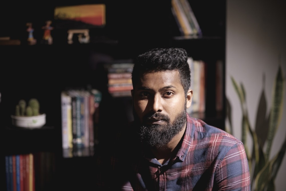 a man with a beard sitting in front of a book shelf