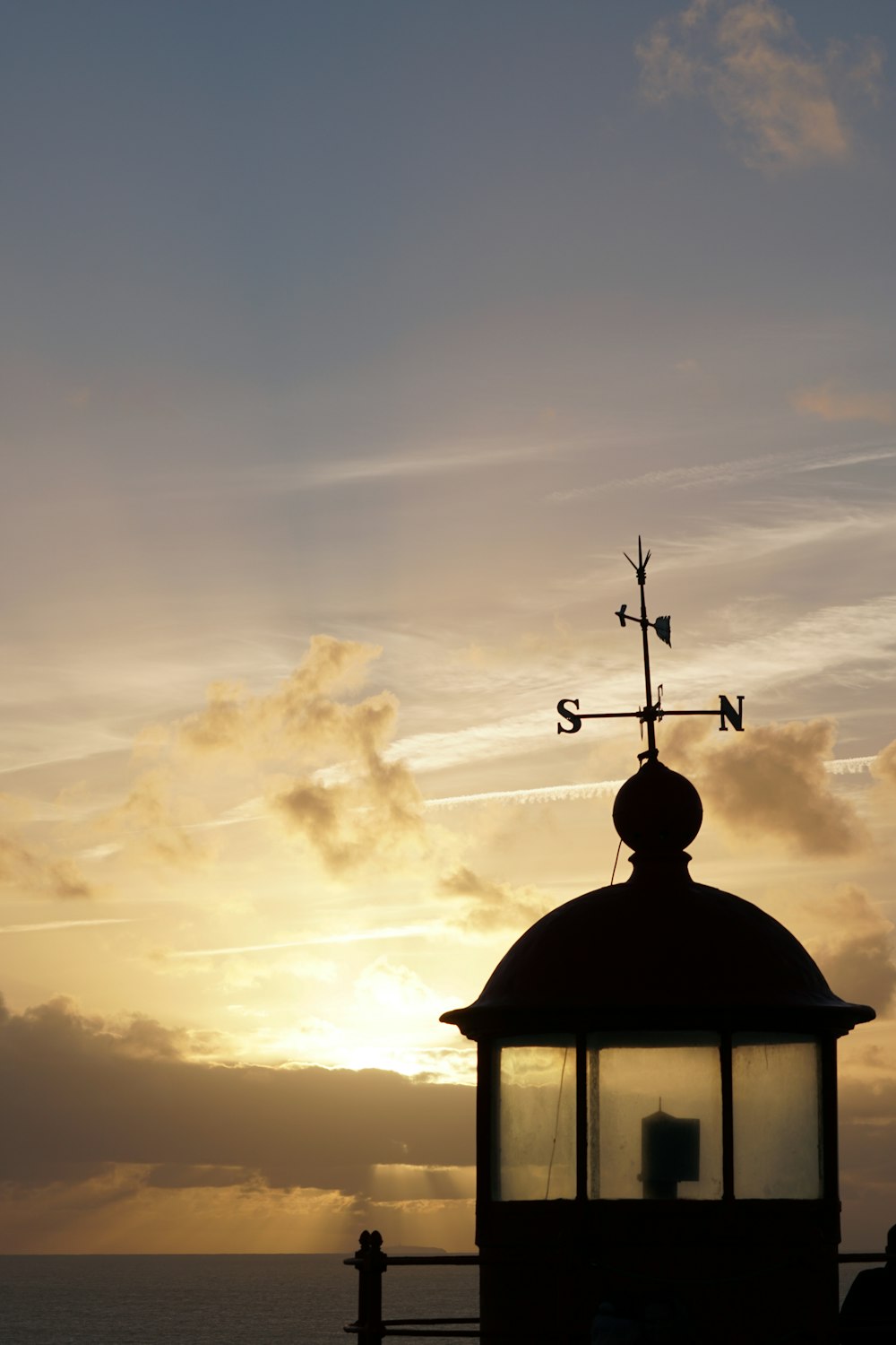 the sun is setting behind a building with a weather vane