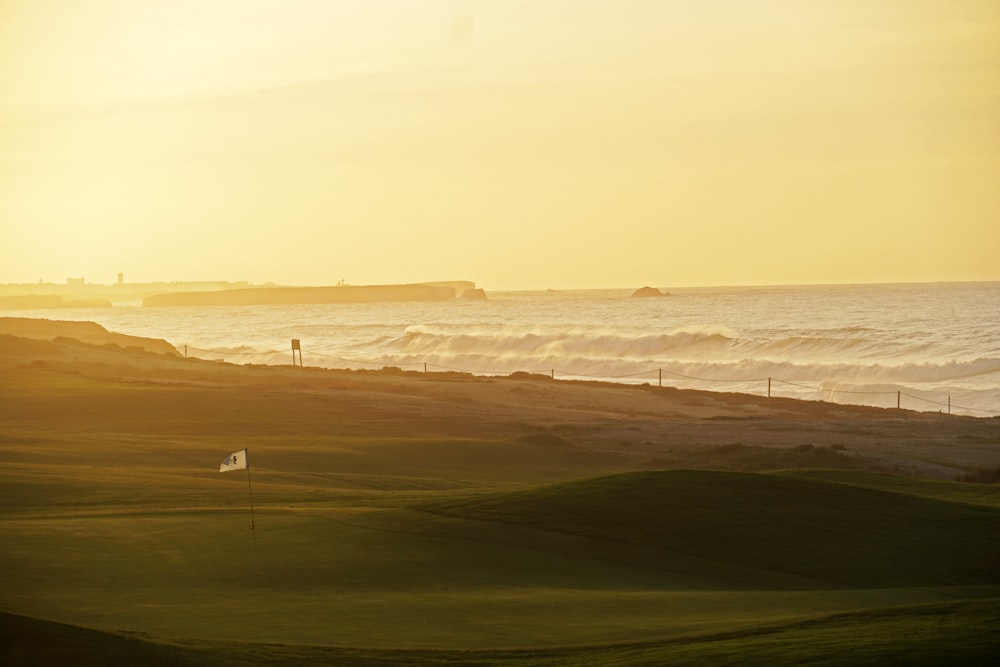 El sol se está poniendo sobre el océano y un campo de golf