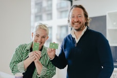 a man and a woman holding up small pieces of paper