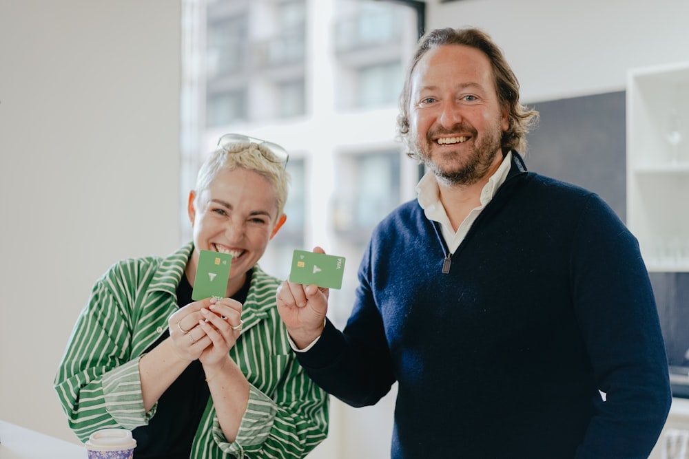 a man and a woman holding up small pieces of paper