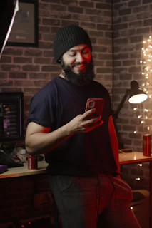 A smiling small business owner checking messages on a smartphone in a cozy office