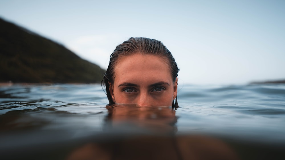 a woman swimming in the ocean with her head above the water