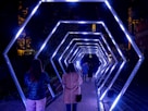 a group of people walking through a tunnel of lights