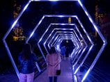a group of people walking through a tunnel of lights