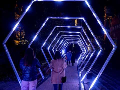 a group of people walking through a tunnel of lights