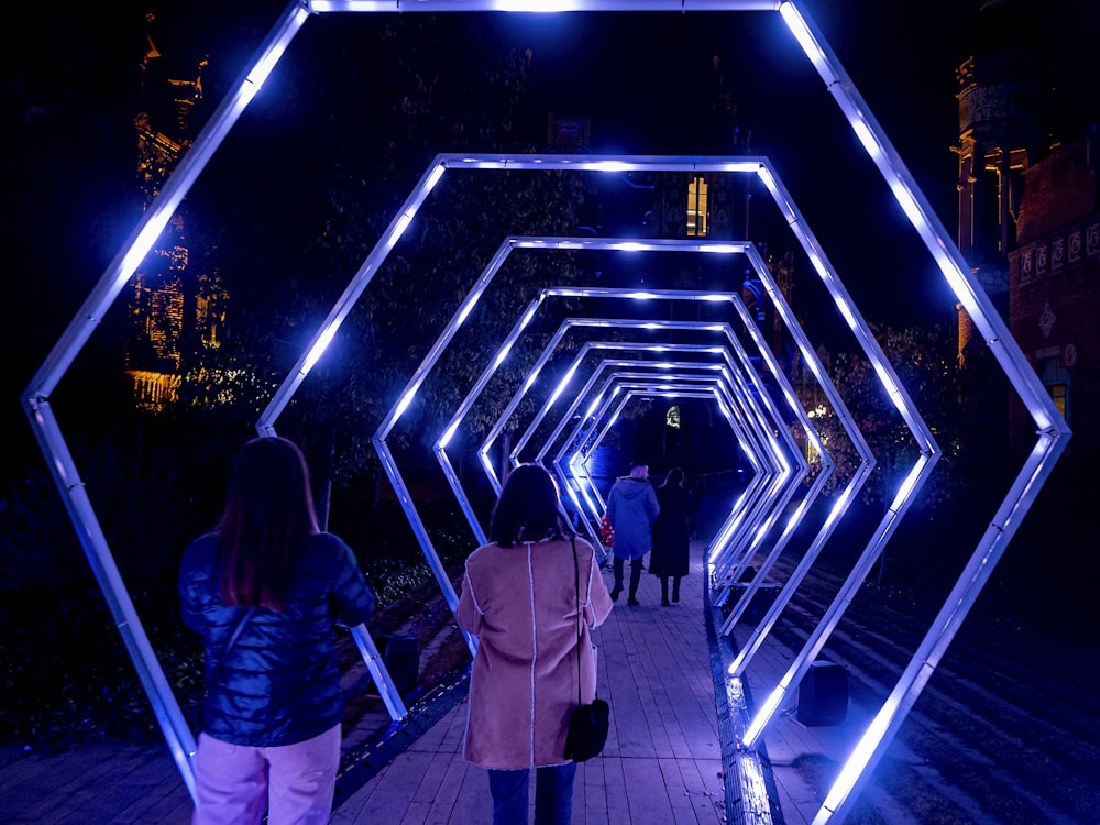 a group of people walking through a tunnel of lights