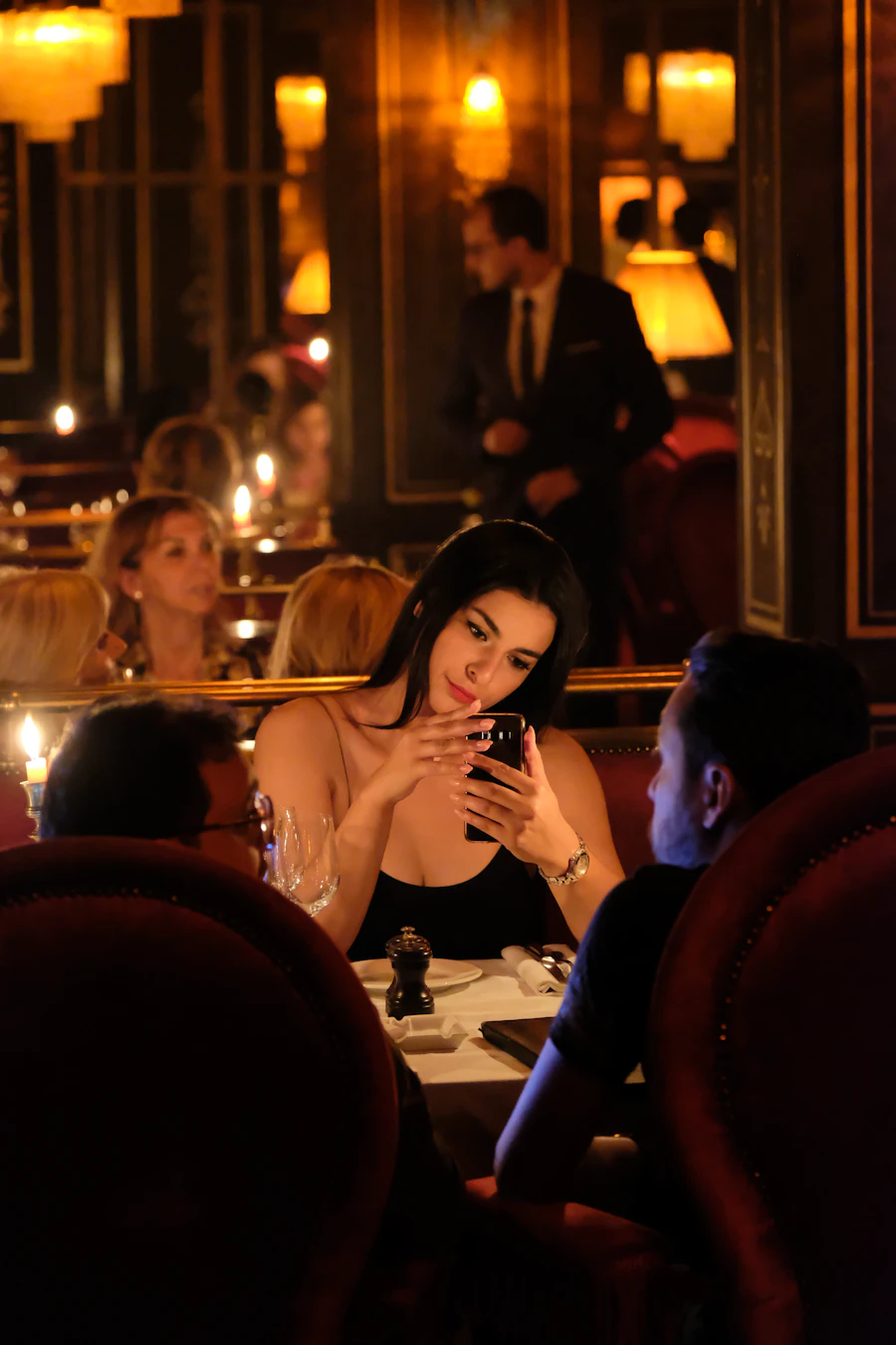 Mujer revisando su teléfono en la mesa de un restaurante al anochecer