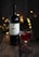 A bottle of red wine, labeled 'VIDENCIA', is set on a rustic wooden surface. Beside it is a glass of the same red wine, filled partially. The background is softly illuminated by warm, golden bokeh lights, creating a cozy and inviting atmosphere. Nearby, small red berries are scattered on the table, adding a touch of natural elegance.