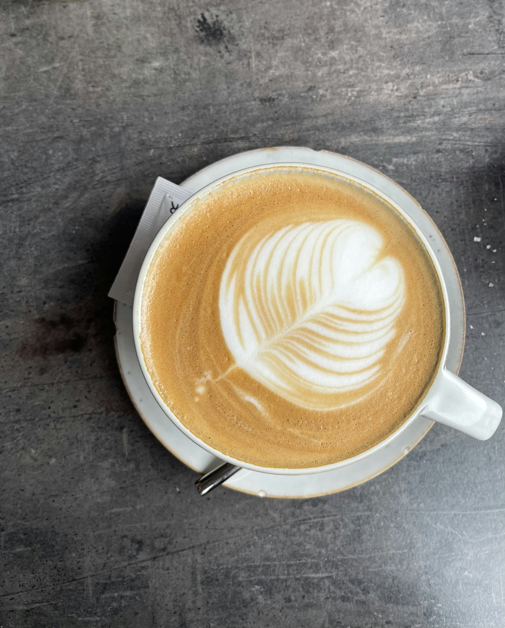 a cup of coffee with a leaf drawn on it