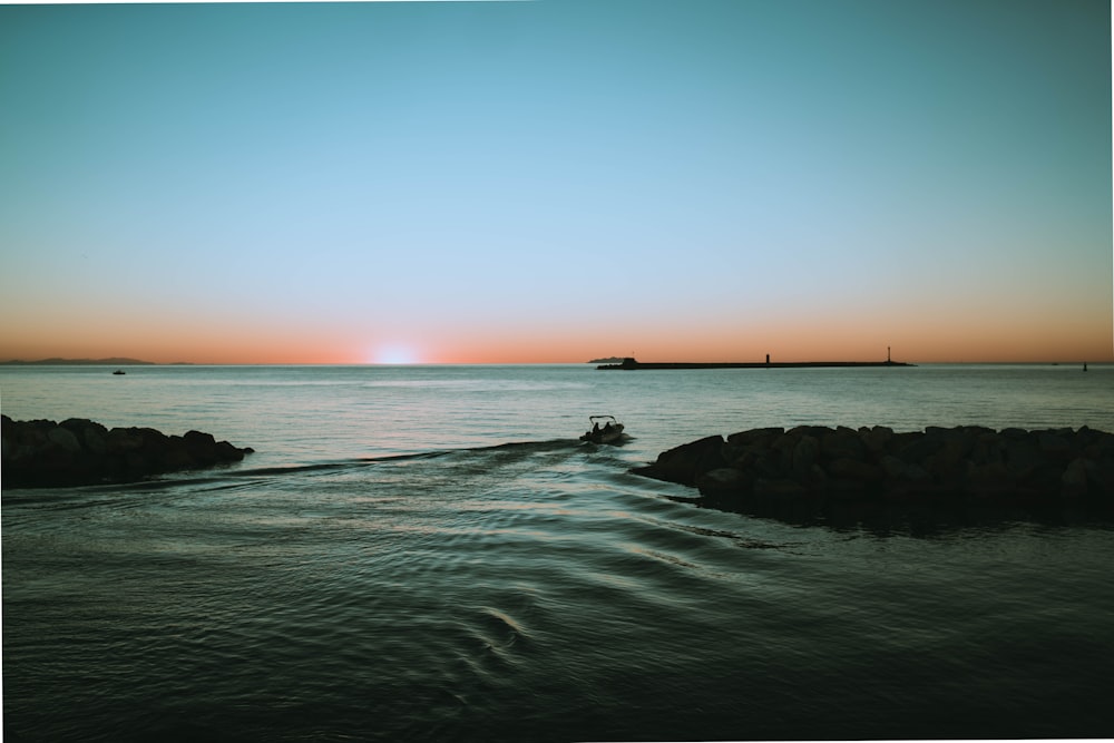 a boat traveling through a body of water at sunset