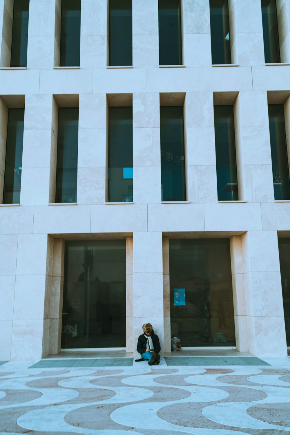 a woman sitting on the ground in front of a building