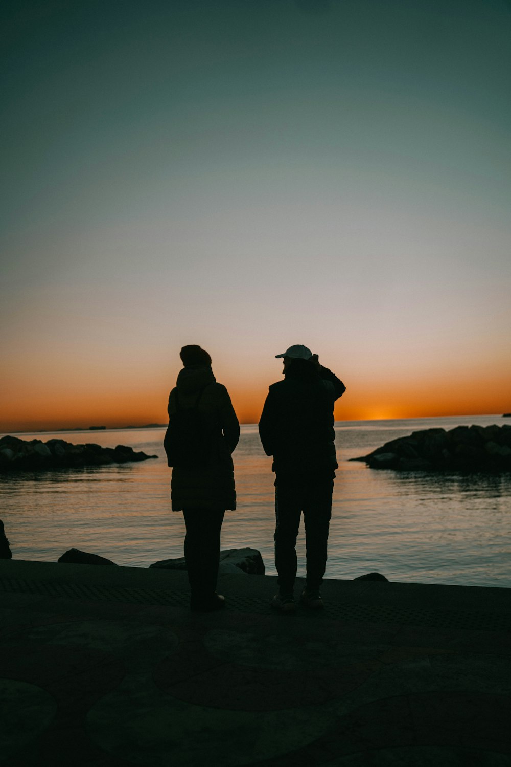 a couple of people standing on top of a beach