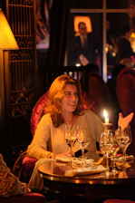 a woman sitting at a table with wine glasses